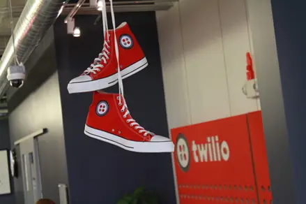 Red high-top sneakers with Twilio logo hanging in an office.
